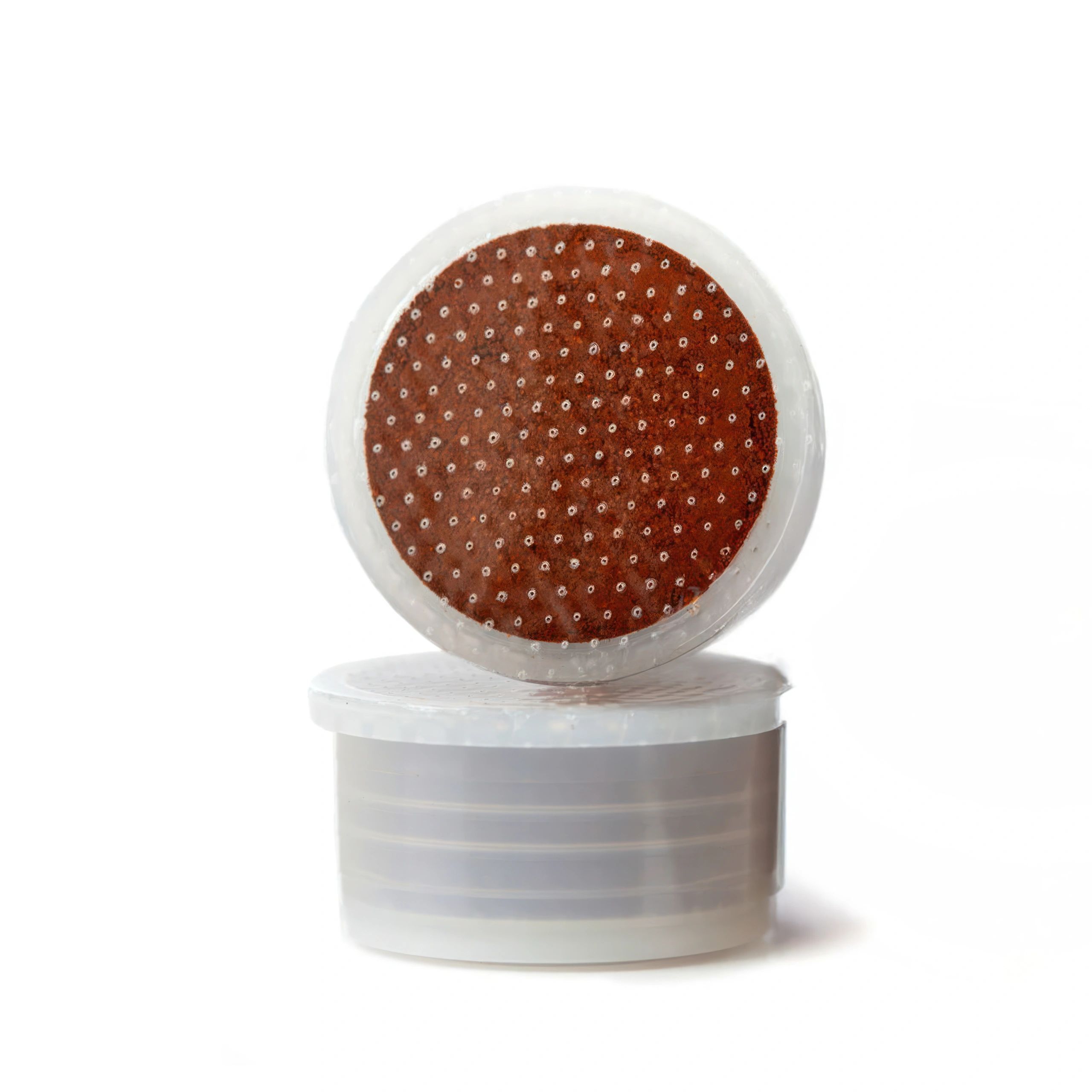 Two coffee pods balancing on a white background