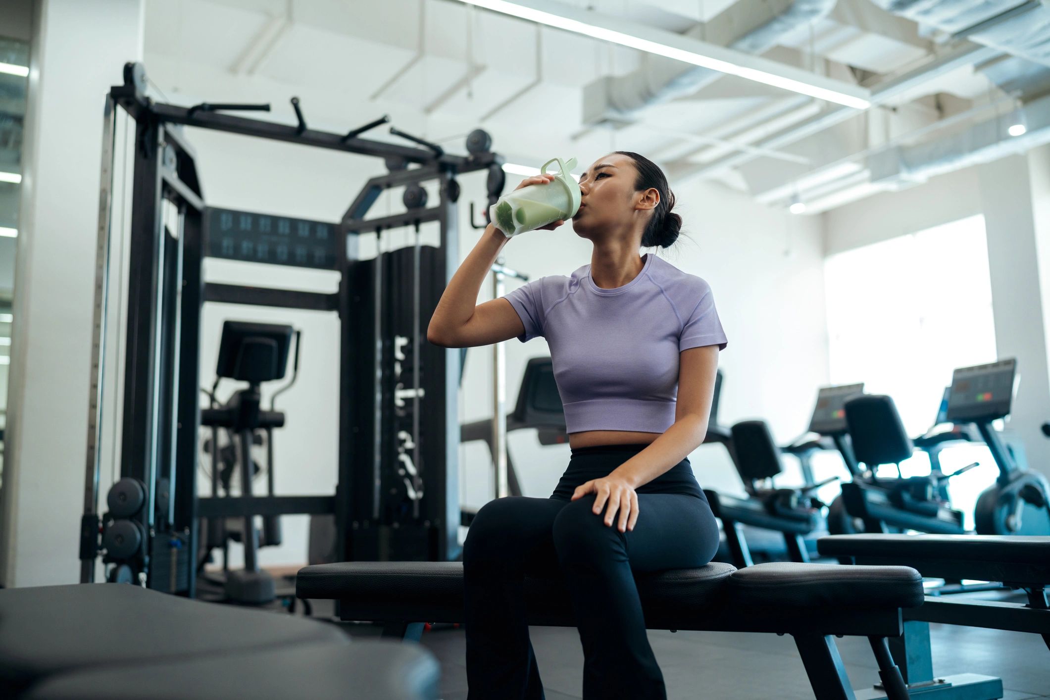Active woman relaxing in a modern gym with a smoothie